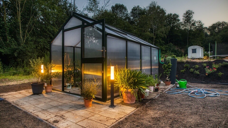 Osvetlený skleník s rastlinami na záhrade