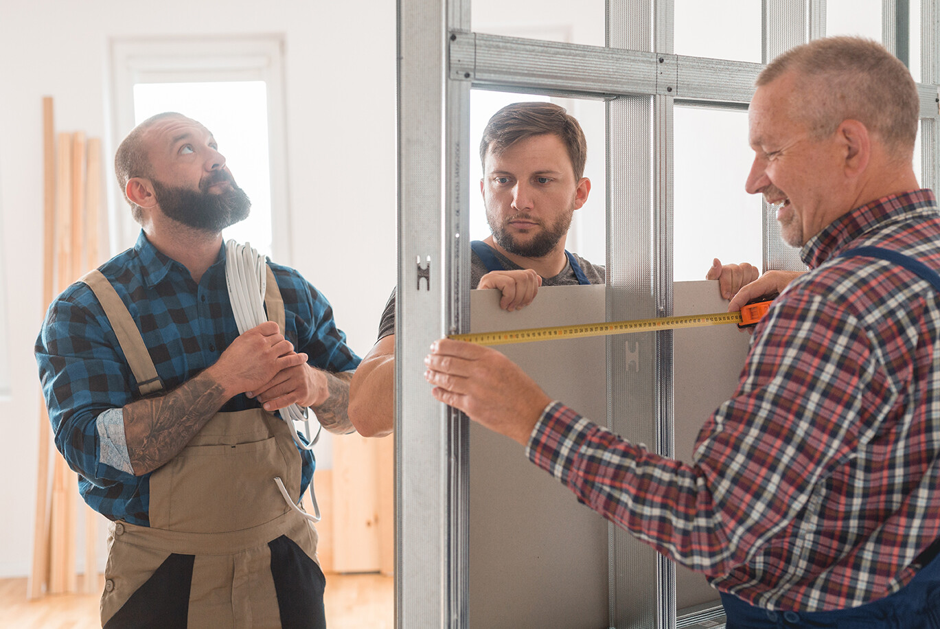 Three builders in uniforms working in a team by house renovation