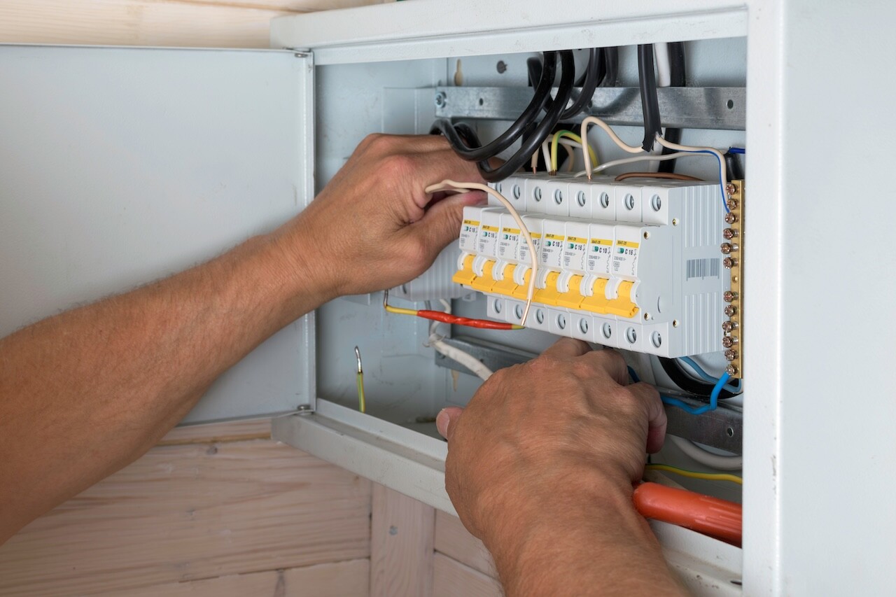 Electrician's skilled hands install wires inside distribution board, ensuring reliable and safe electrical connection in new home.