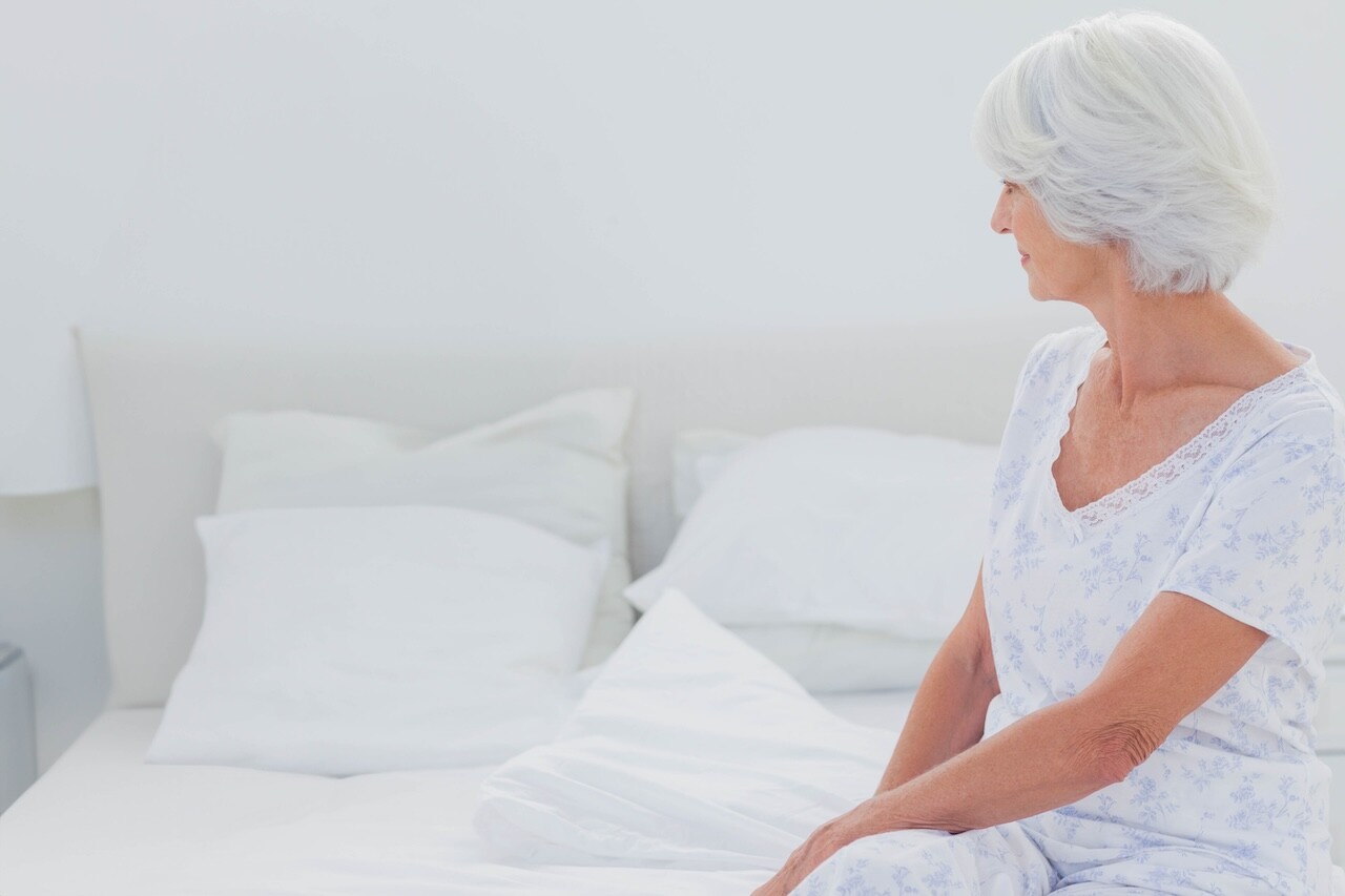 Woman looking at husband reading newspaper in the bed